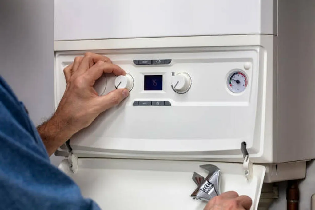 Essential Guide to Winter Heating System Prep & Maintenance 3 Technician adjusting the thermostat on a heating system, emphasizing maintenance for energy efficiency and safety in winter preparation.